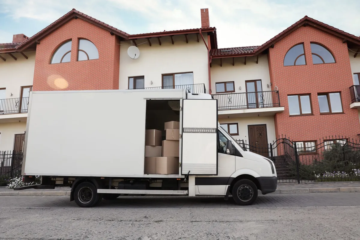 A van filled with moving boxes parked near a new house, illustrating the moving process.
